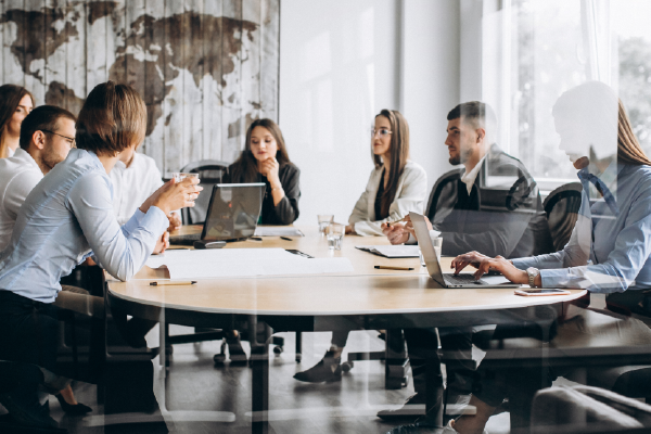 A photo of a group of people sitting around a conference table in a business office.