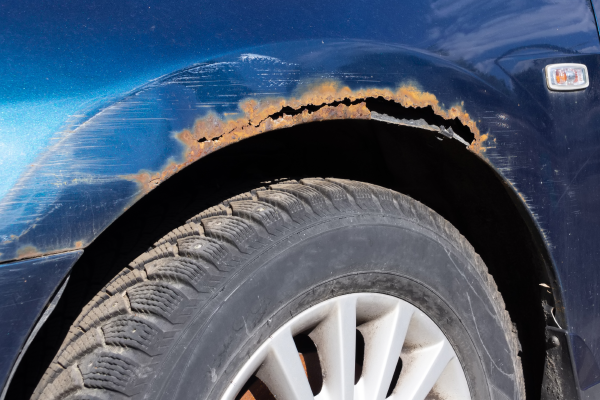 A photo of rust on the rim of the wheel well on a blue car.